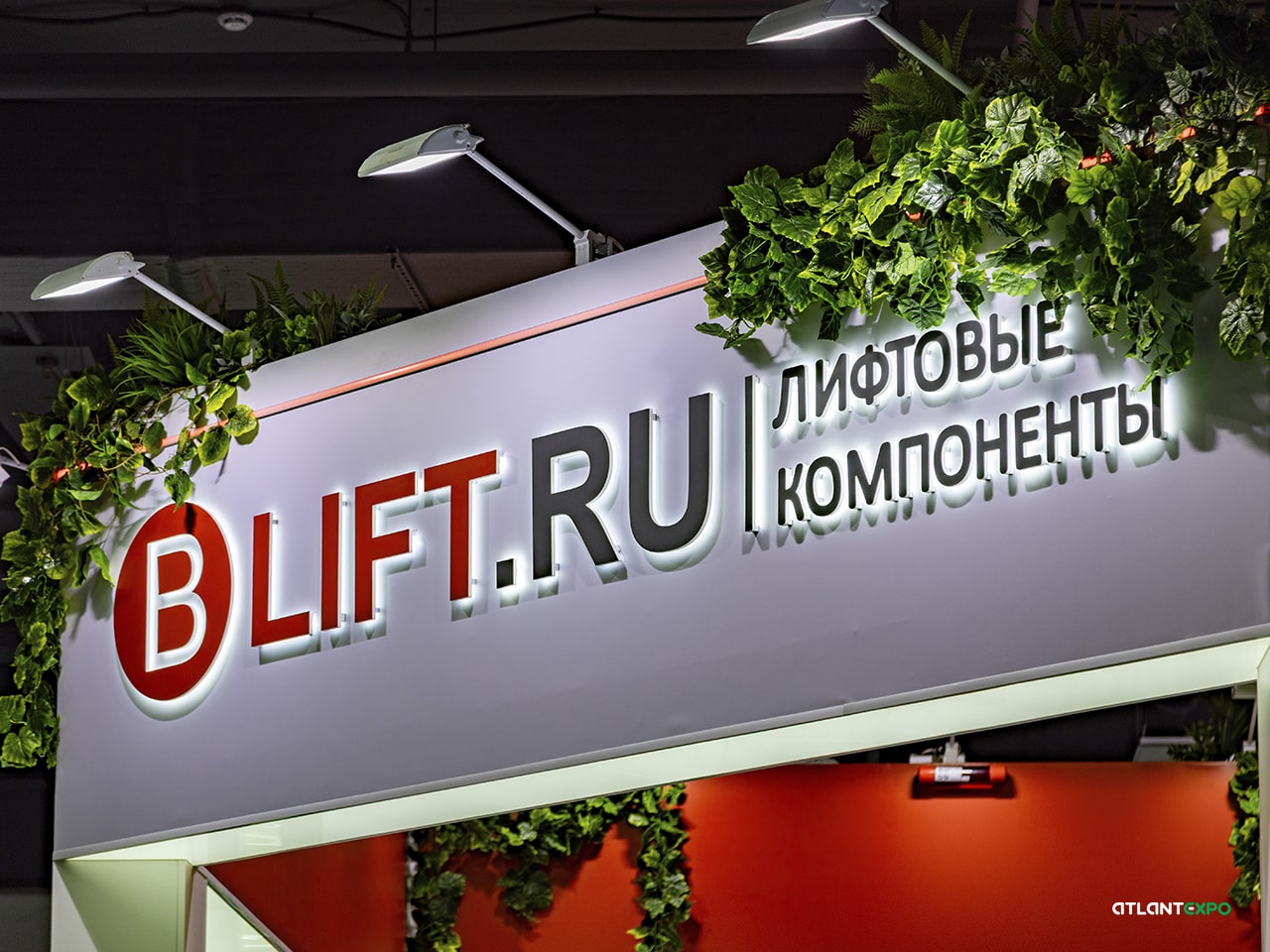 Фриз выставочного стенда окружен зелеными растениями, которые придают стенду свежесть и естественность, образуя эффектный зеленый декор. Логотип с контражурной подсветкой притягивает взгляды посетителей выставки, вызывая желание зайти на стенд B LIFT.